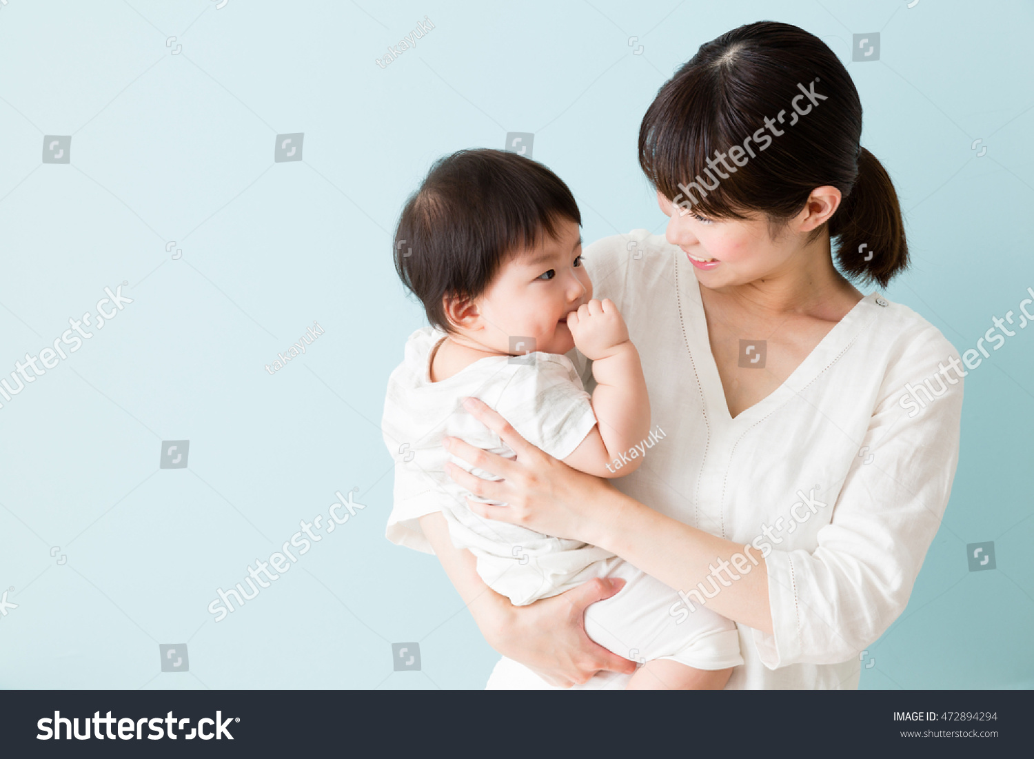 portrait of asian mother and baby isolated on blue background