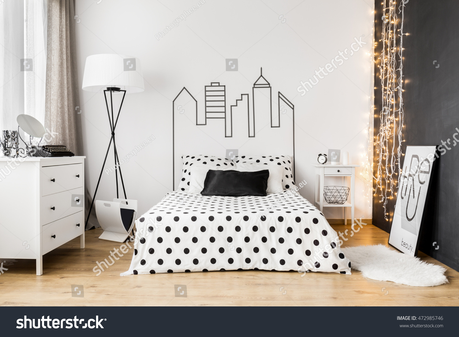 Bright bedroom interior with wide bed  commode and one black wall
