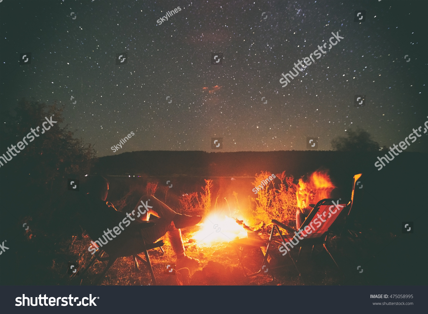 Two friends are sitting around a campfire and just relaxing