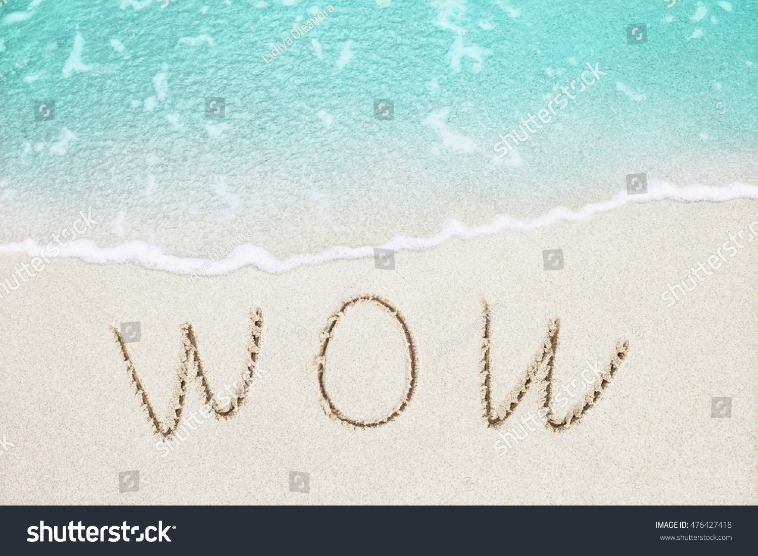 Wow handwritten on the sandy beach with beautiful soft azure wave on background