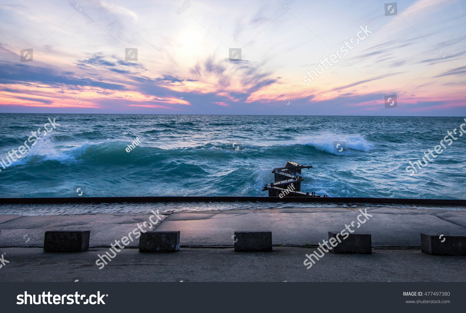 Waves And Lake Michigan Sunset. The sunset over the coast of the Lake Michigan horizon during a gale warning. Lake Michigan is the third largest of the Great Lakes.