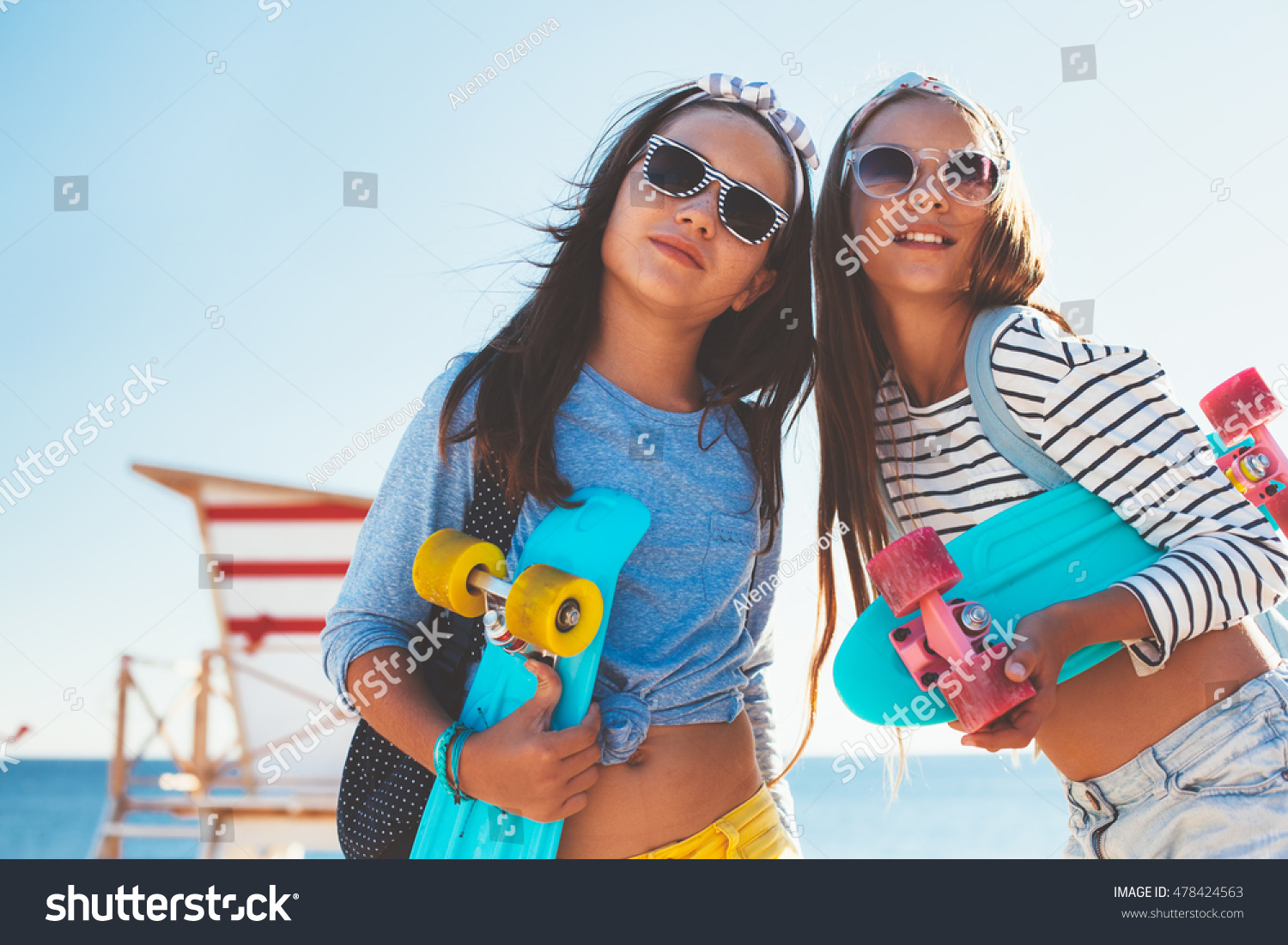 Two 10 years old children wearing cool clothing posing with colorful skateboards on the beach  urban style  pre teen summer fashion.