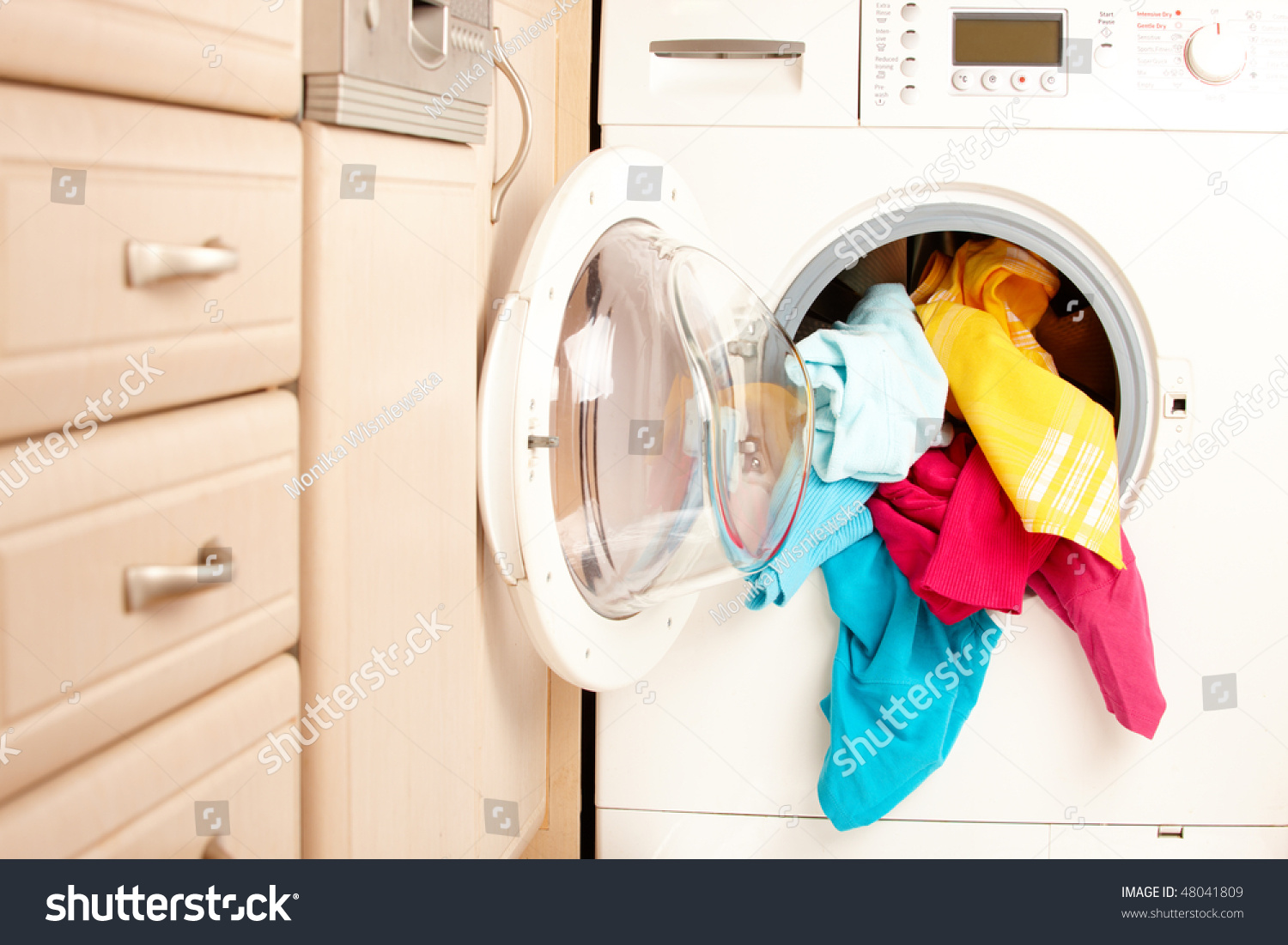 Close-up on a washing machine with clean colorful clothes
