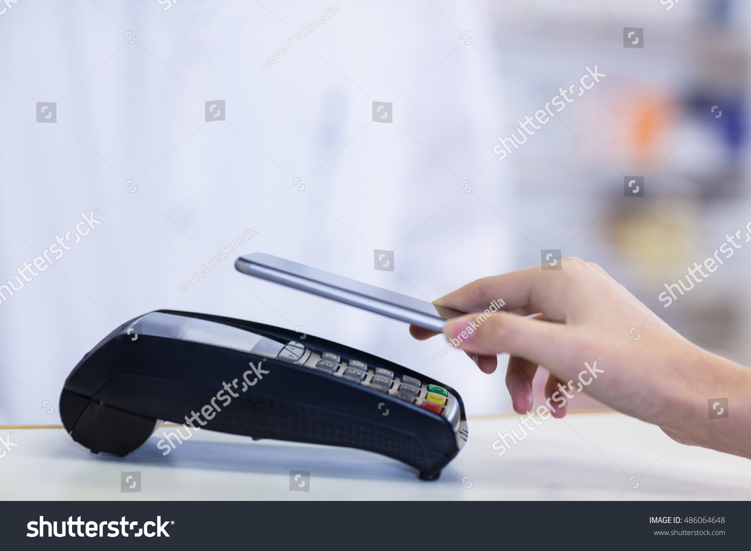 Woman paying bill through smartphone using NFC technology in pharmacy