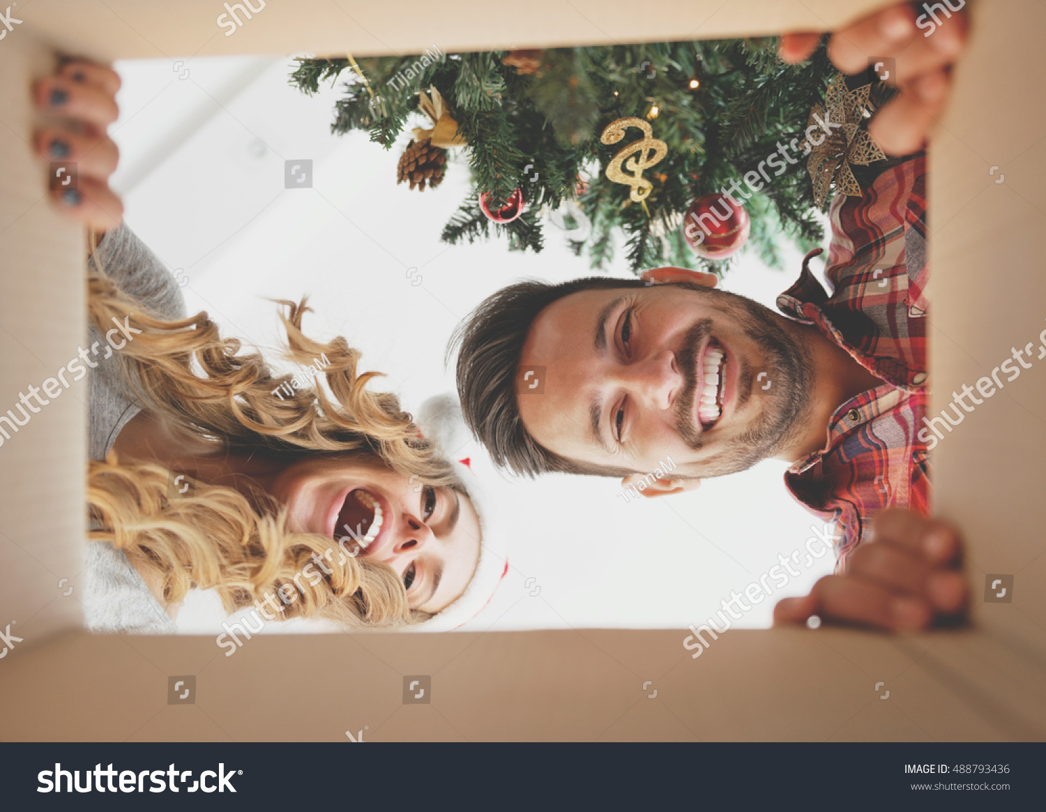 Young couple opening a Christmas present  view from inside of the box