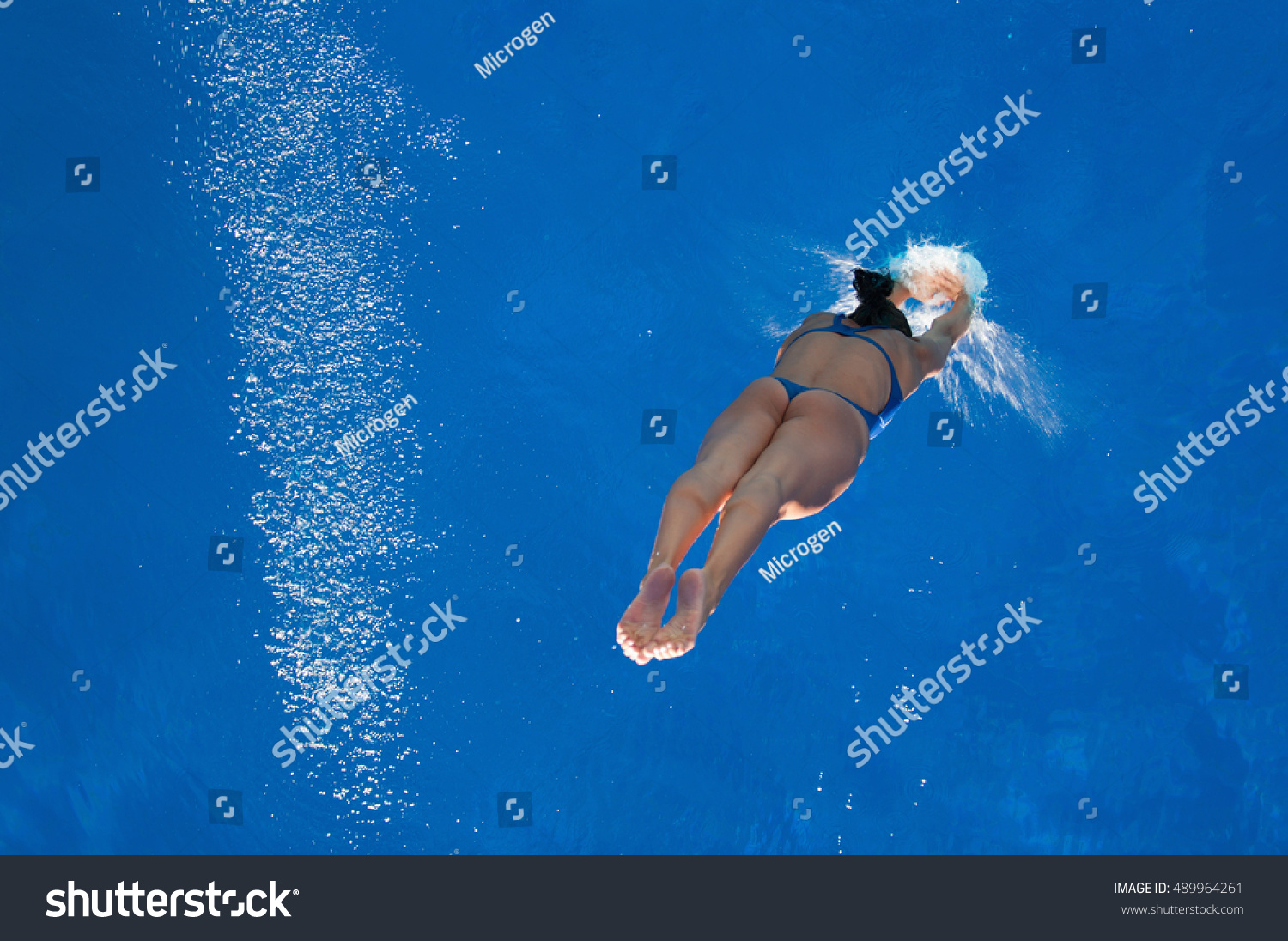 Woman diver in the moment of touching water surface. Lots of copy space  rotatable.