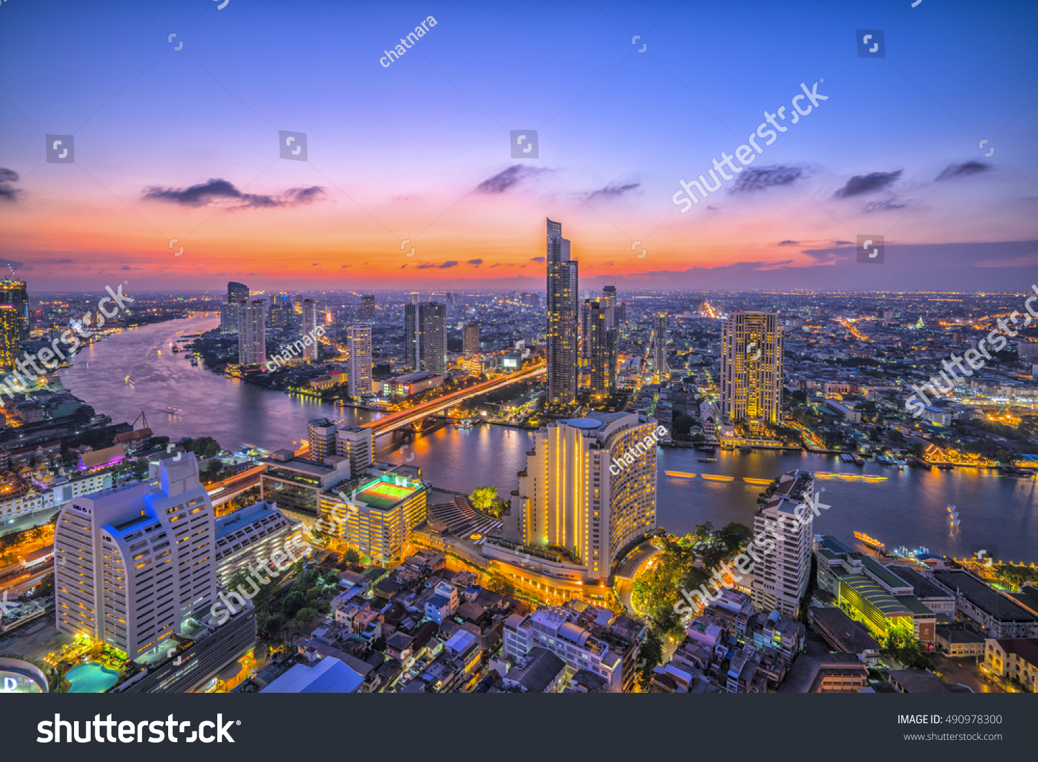Curve of Chao Phraya River and river side view. In a main business zone of Bangkok. It's combining a contrast of shining buildings and blackening living houses. With a colorful twilight sky.