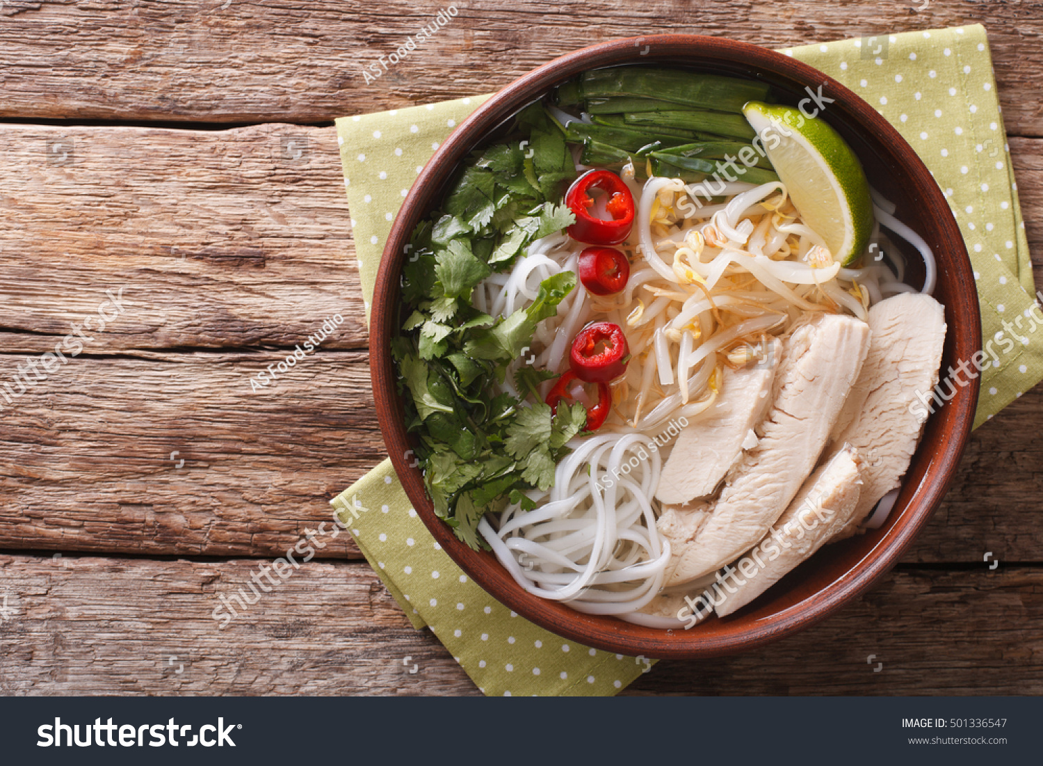 Vietnamese soup Pho Ga with chicken and rice noodles bean sprouts and chilli in a bowl close-up. Horizontal view from above