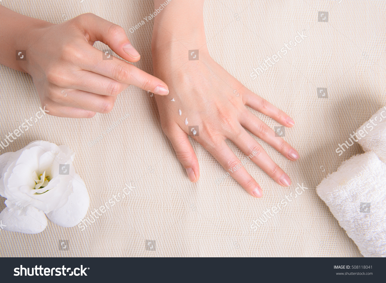 Close up top view of young woman applying cream on hand on spa table