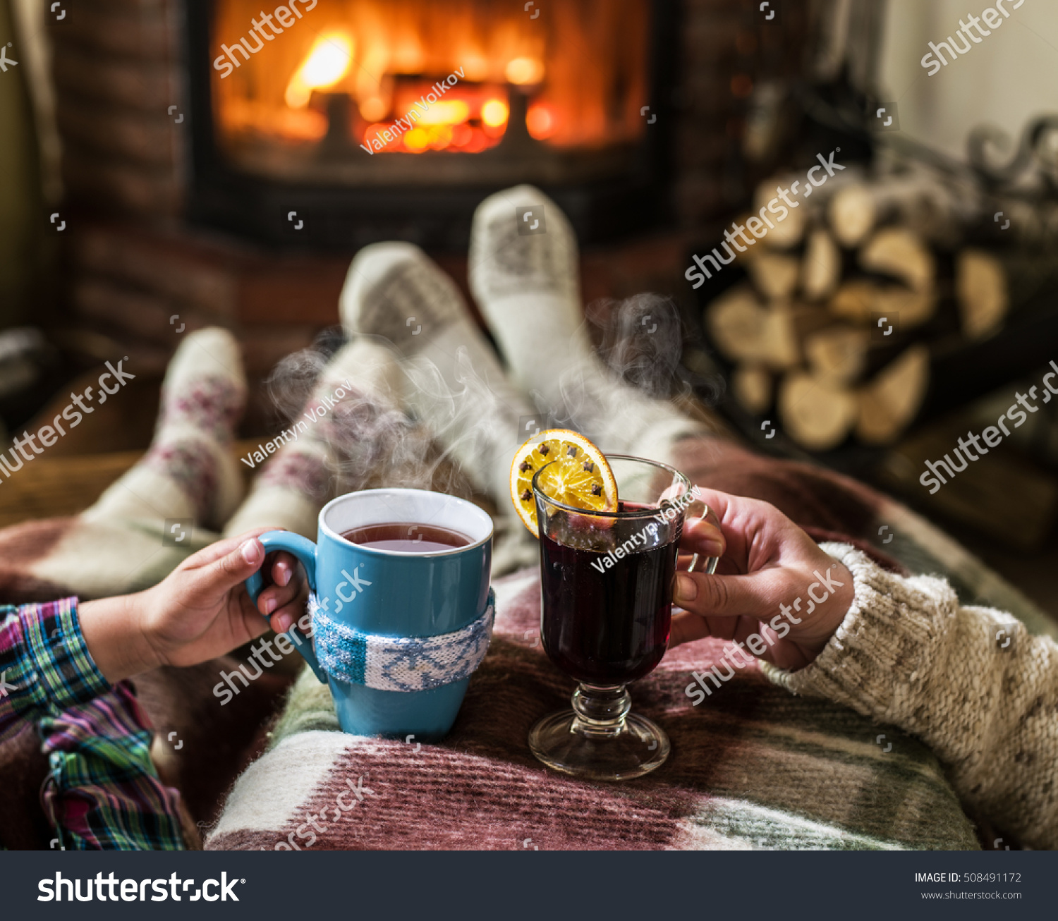 Warming and relaxing near fireplace. Woman feet near the cup of hot drink in front of fire.