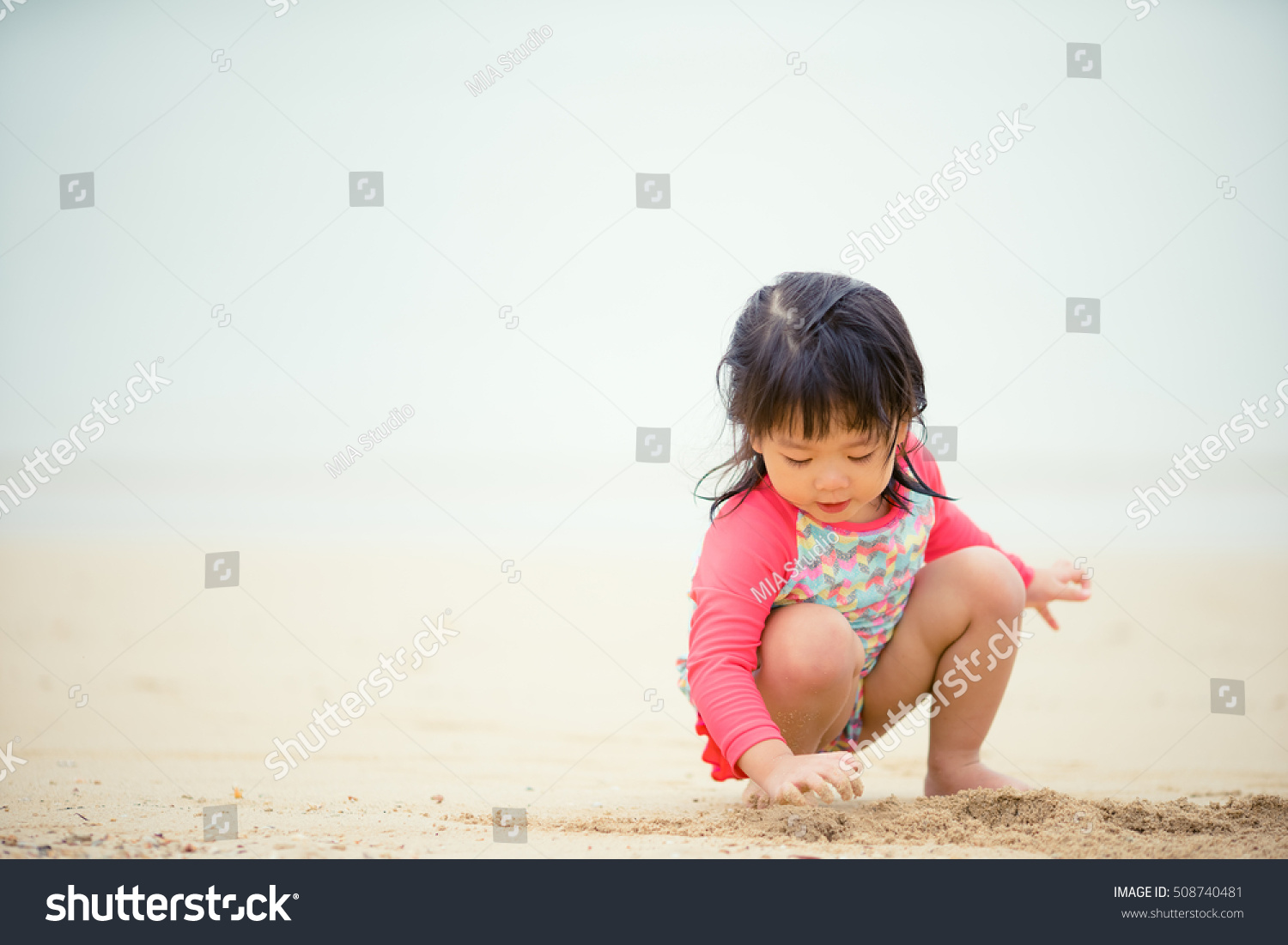 Little asian girl playing on beach.