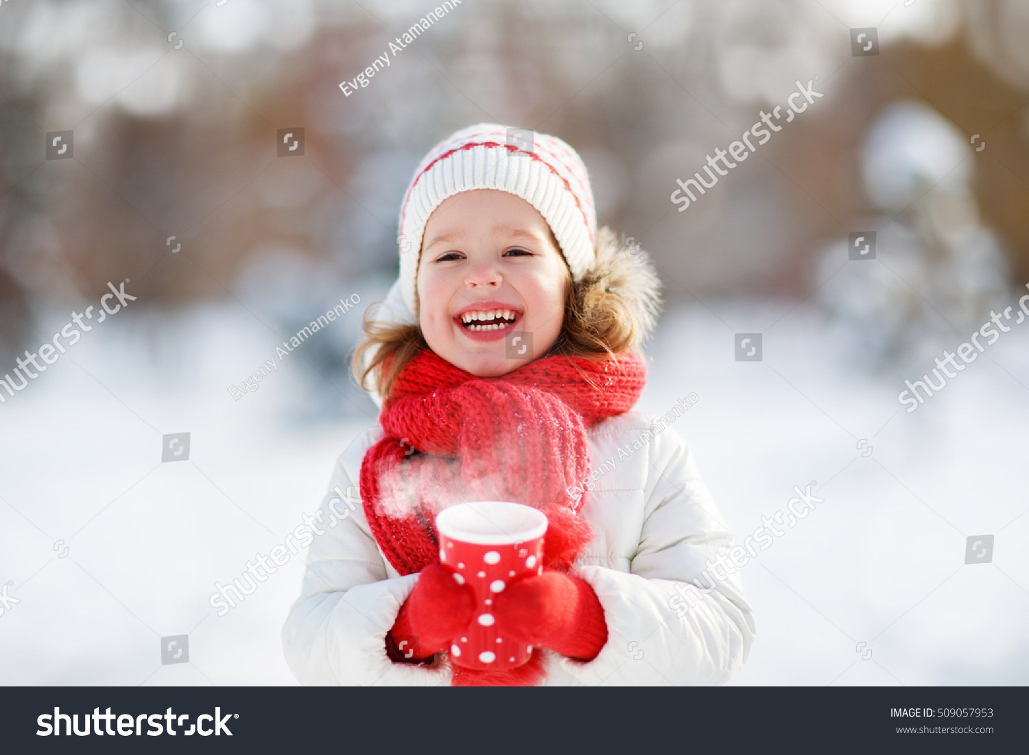 Happy child girl with a cup of hot tea in winter  walk outdoors