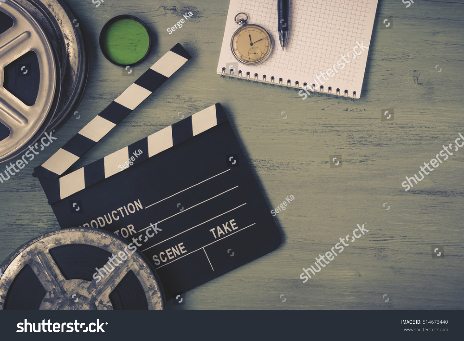Clapperboard and a film reel  a stop watch  a notebook and a lens on the table