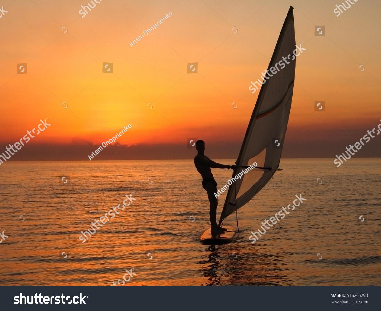 windsurfer silhouette against a sunset background - natural sky