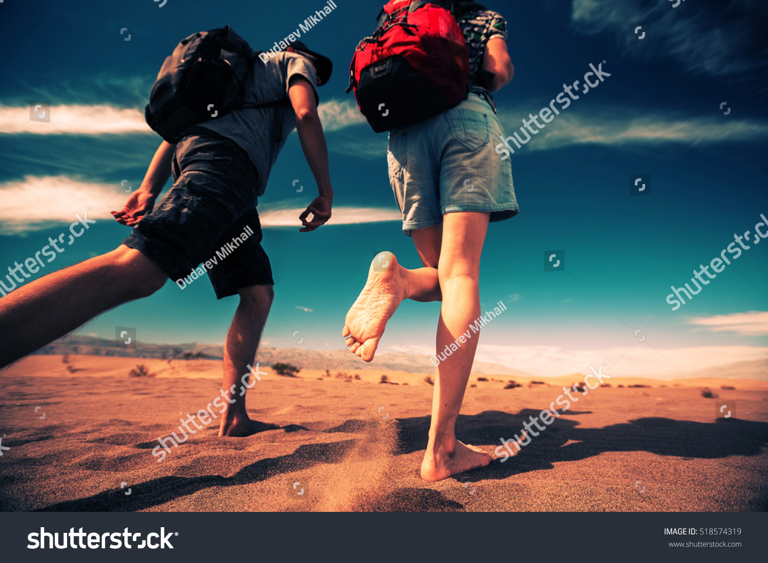 Two hikers walking forward in the sandy desert of the Death Valley National Park  USA