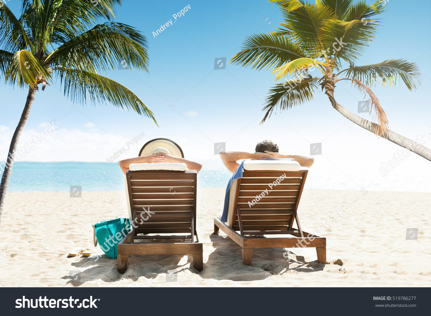 Rear View Of Couple Relaxing On Lounge Enjoying Vacation On Beach