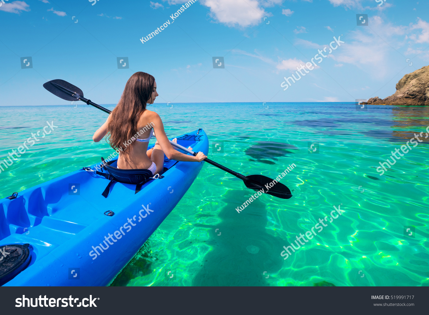 Beautiful young woman kayaking in the sea near the islands. Adventure by kayak.