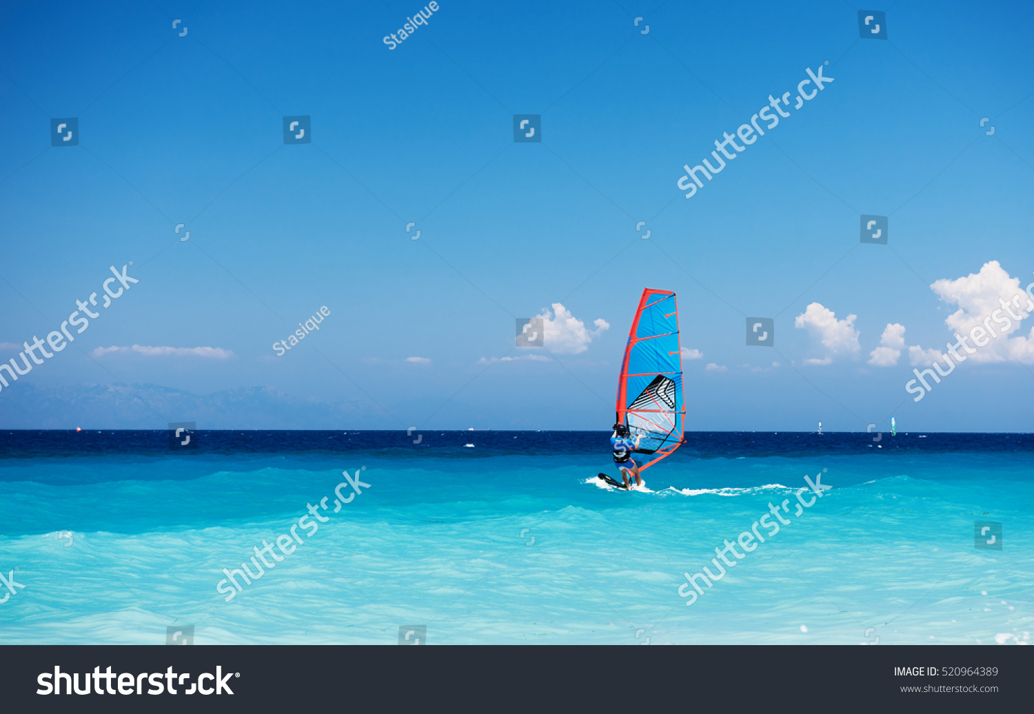 Windsurfing. Lonely surfer exercising on blue water. 