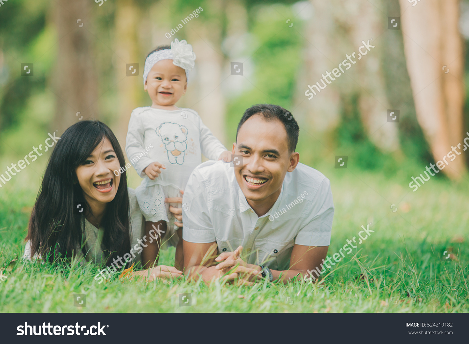 Happy family of three lying in the grass in autumn