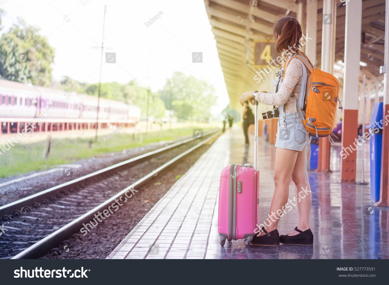beautiful smiling woman traveler with luggage walking on the platform along the passenger train