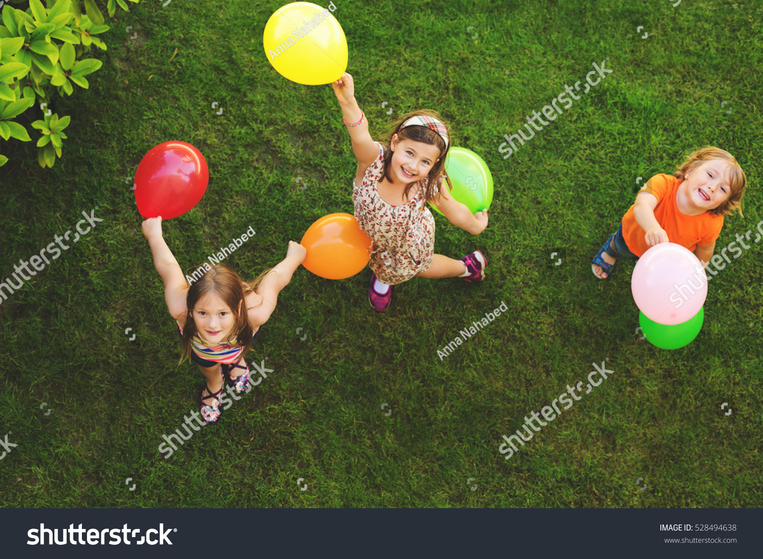 Three happy little kids playing with colorful balloons outdoors  top view