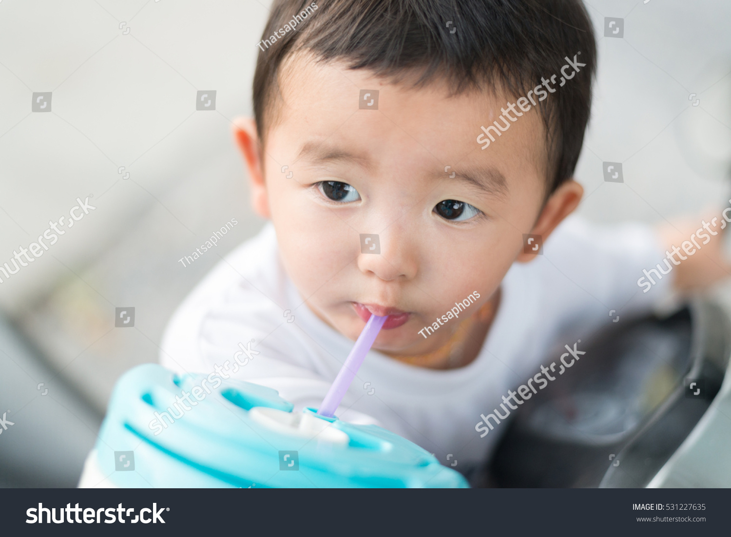 Close up of Asian baby boy drinking water with straw  shallow DOF