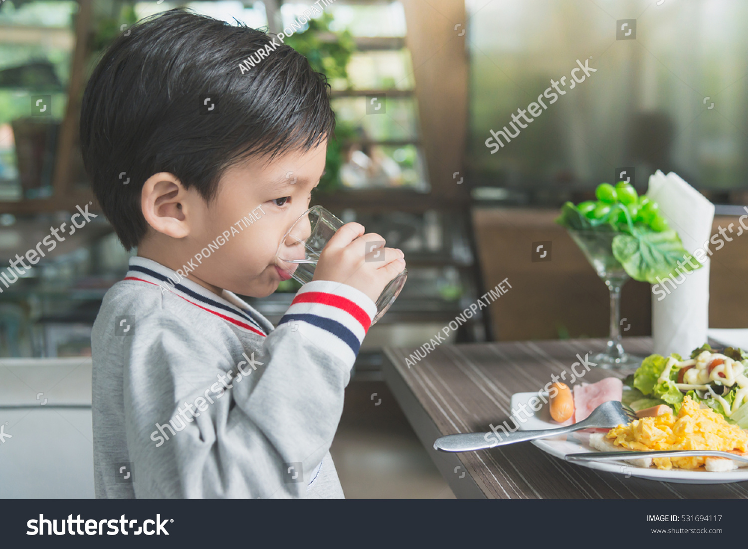 Cute Asian child drinking water in the glass