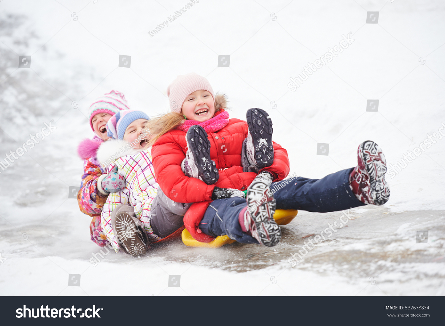 children having fun riding ice slide in winter