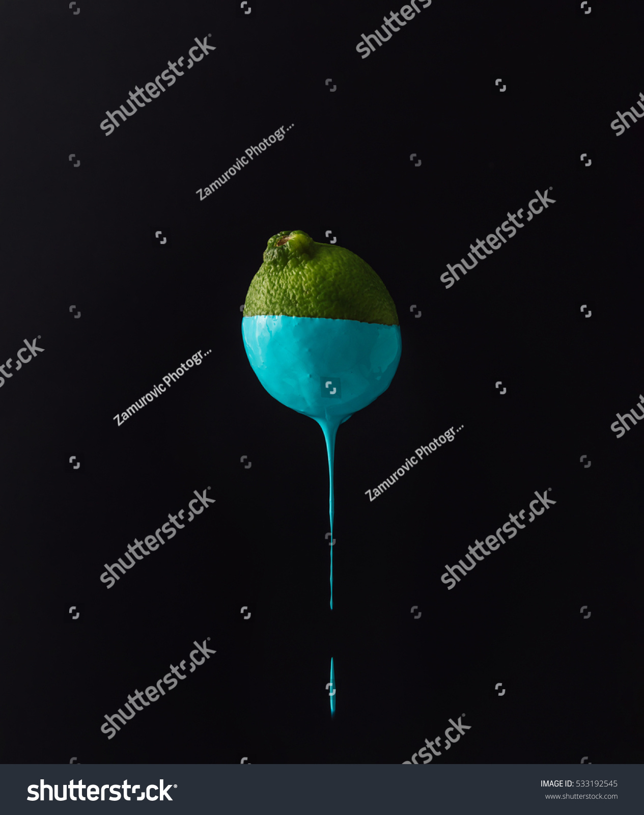 Lime with dripping blue paint on dark background. Minimal food concept.
