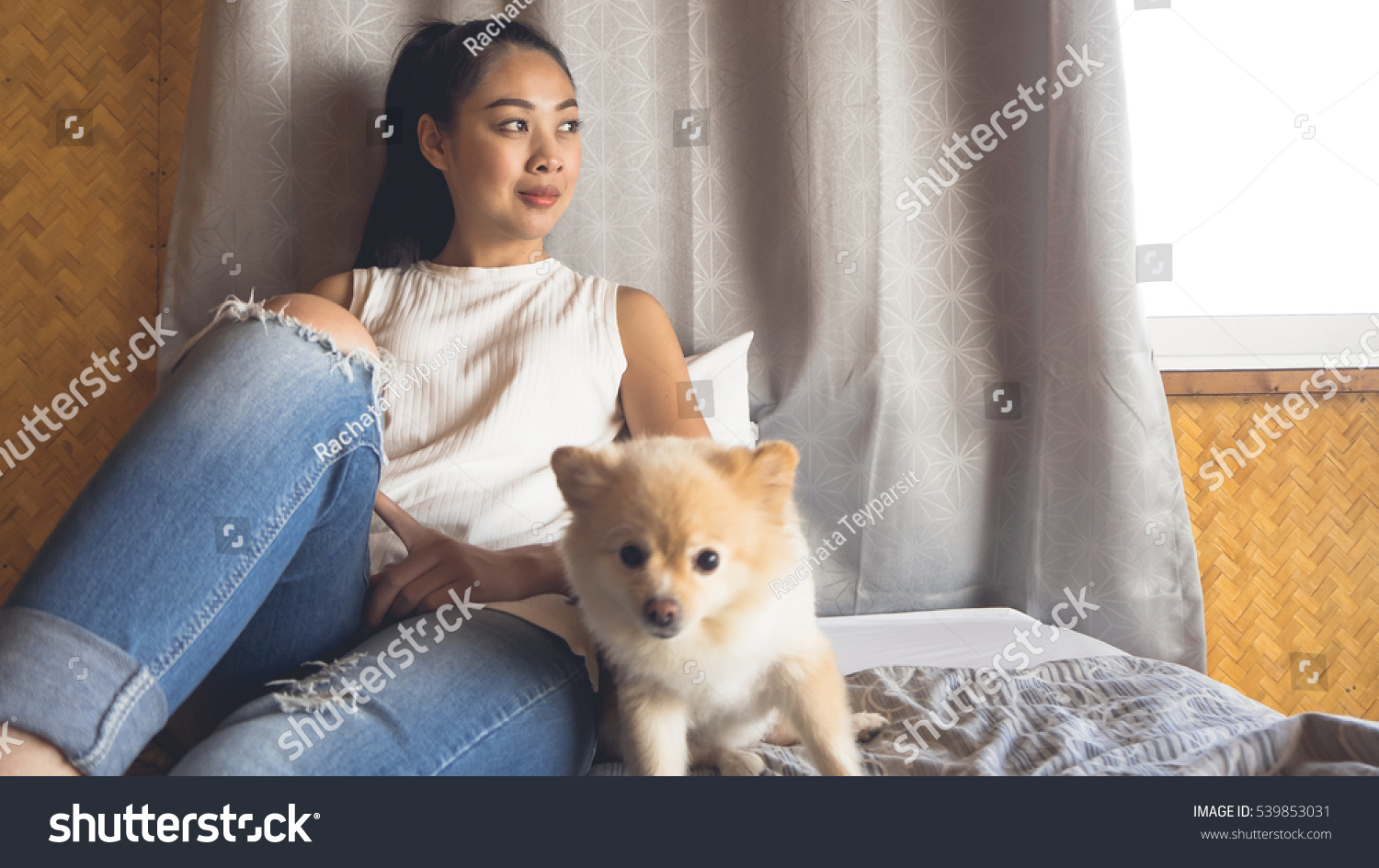 Asian woman relax on bed with her dog in bamboo bedroom.