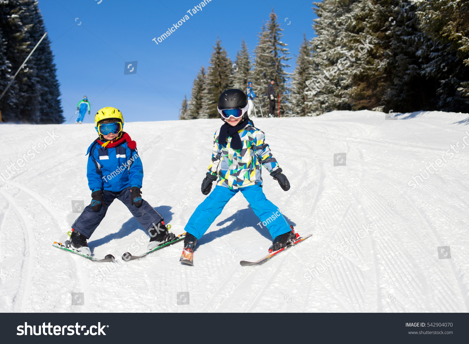 Two young children siblings brothers skiing in Austrian mountains on a sunny day wintertime enjoying sports