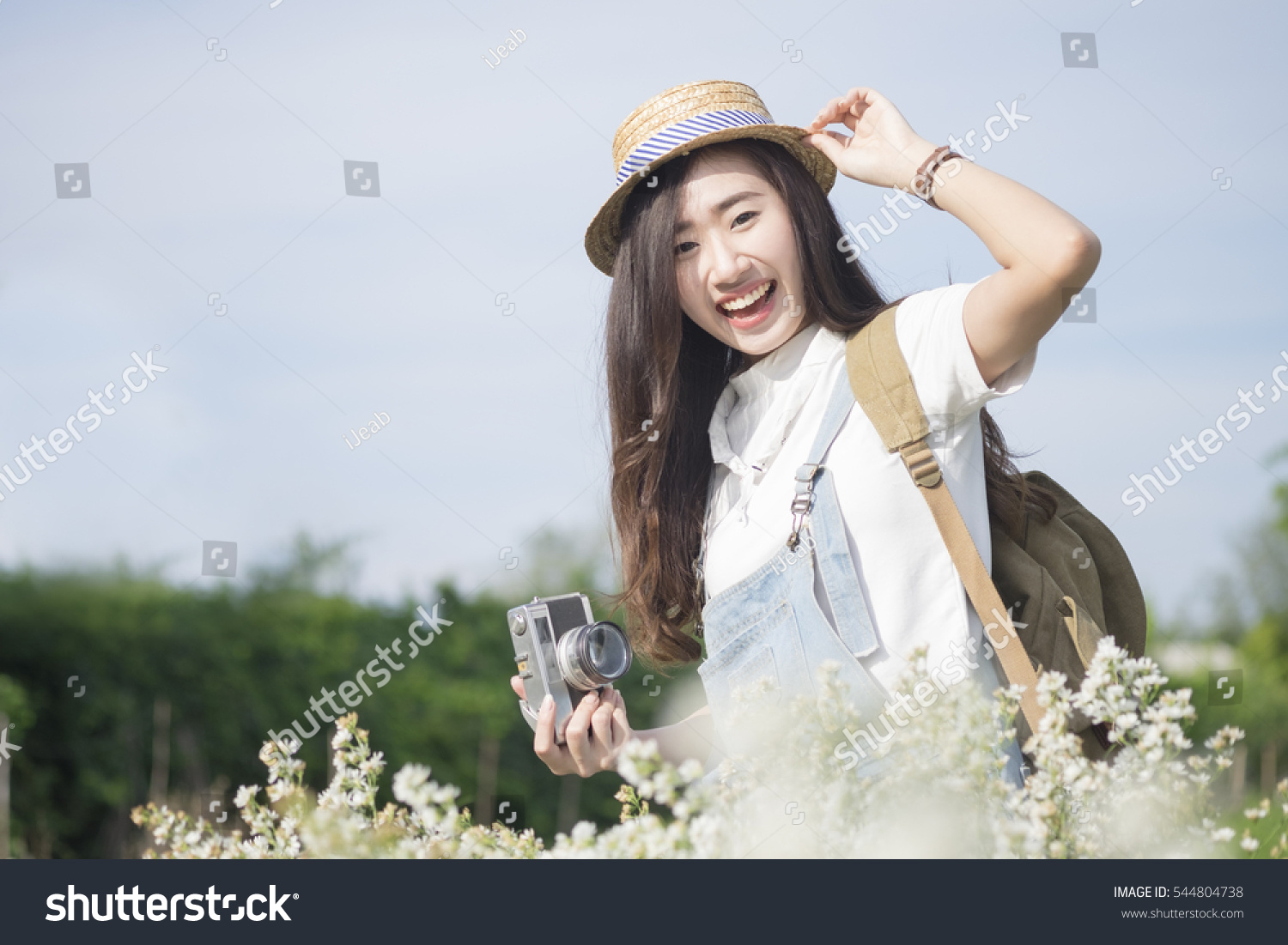 Asian hipster cute teen girl with camera in white flower garden vintage tone travel and relax with nature concept.