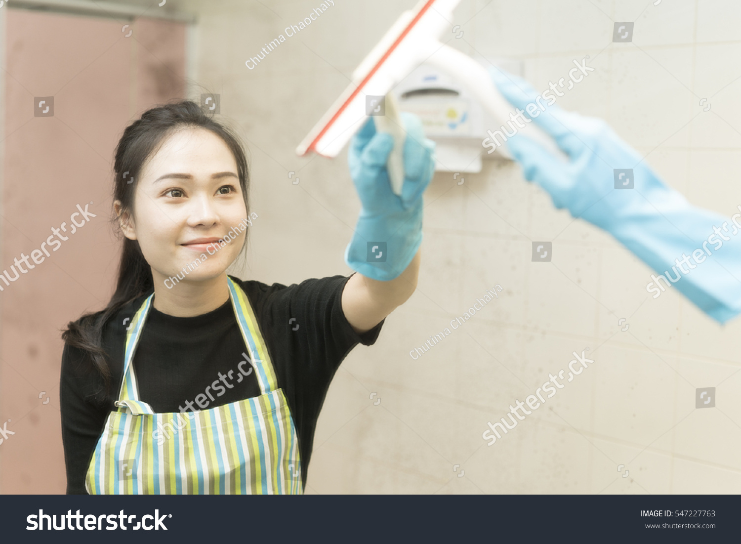 Housekeeping or maid cleaning a dirty mirror in a toilet