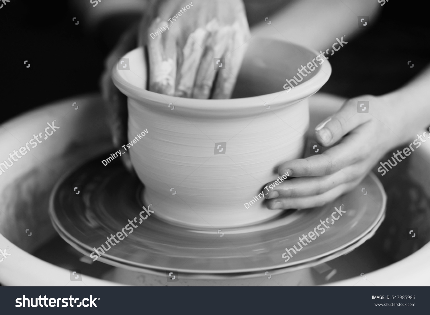 Mother teaches son to work on pottery wheel. Close up of dirty hands sculpting clay.