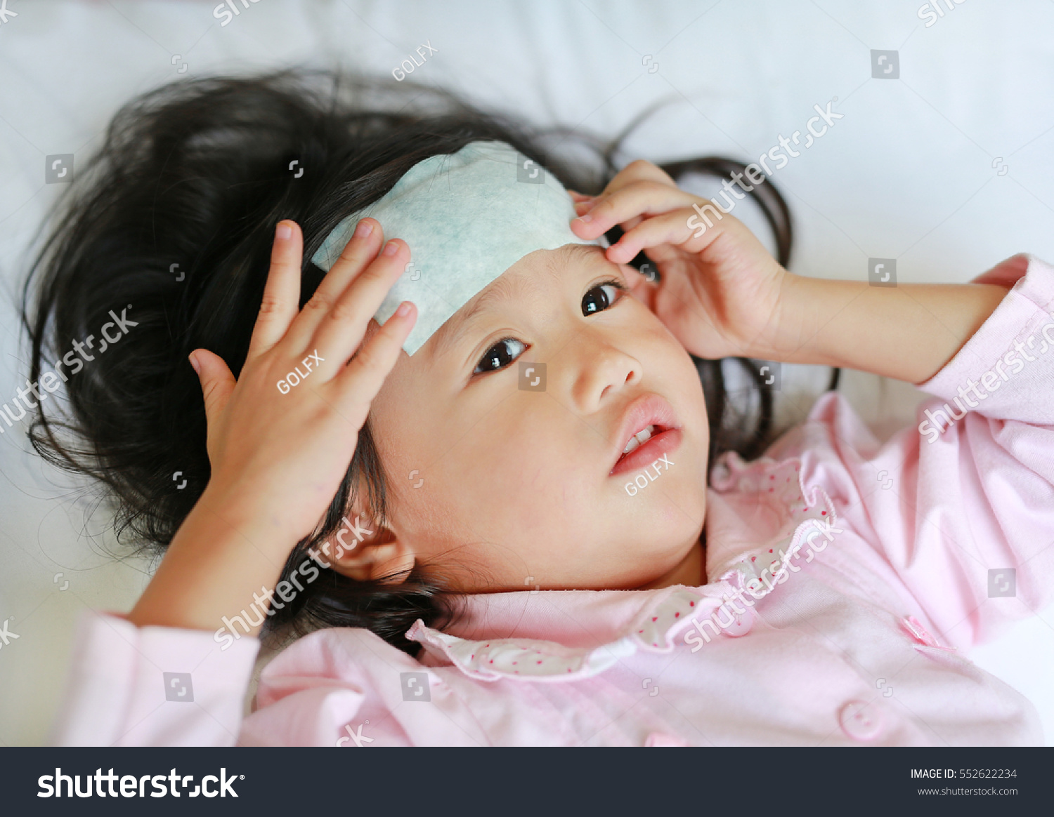 Sick girl lying on the bed with a cool jell on her head.
