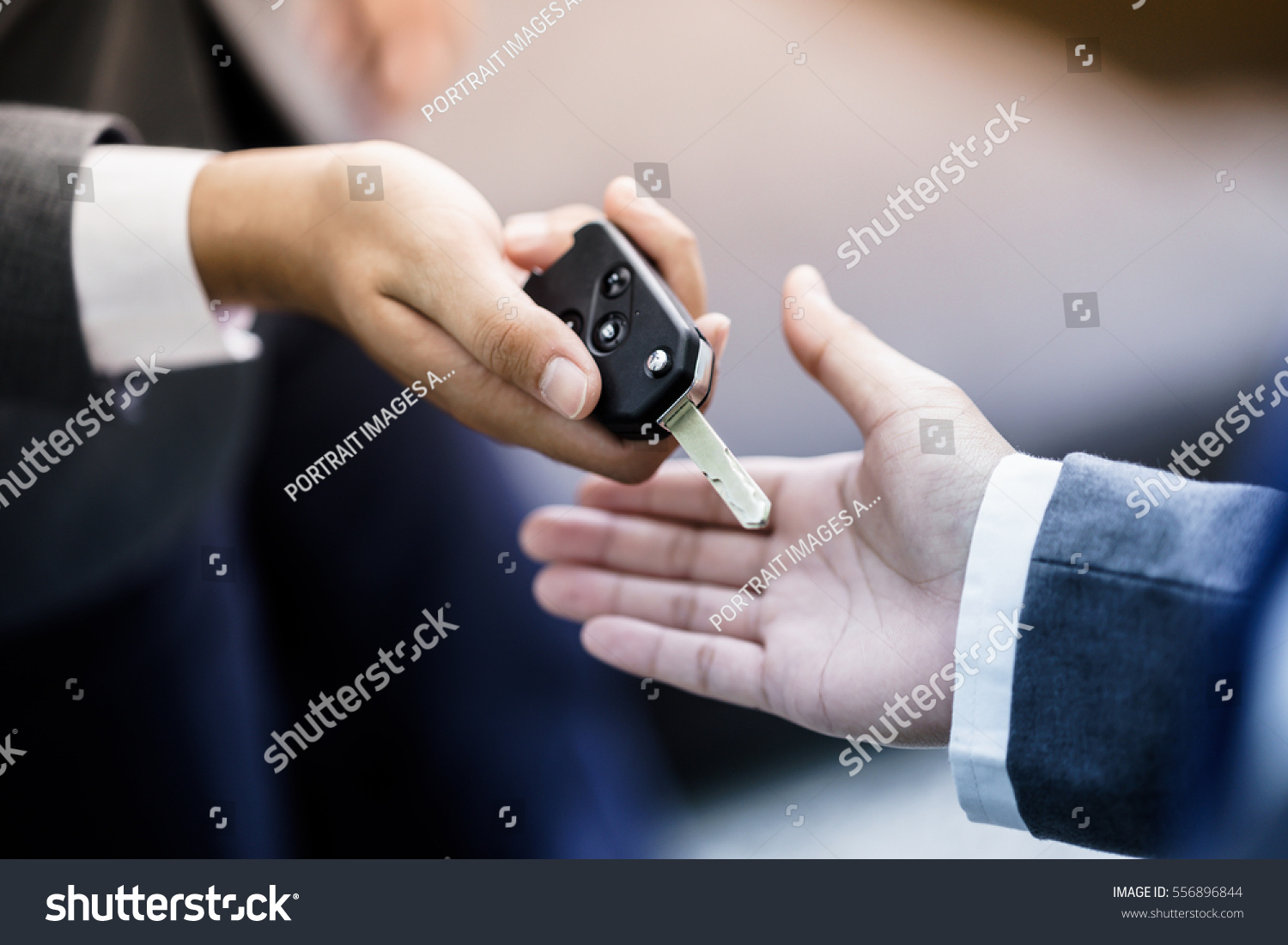 Car salesman handing over the keys for a new car to a young businessman