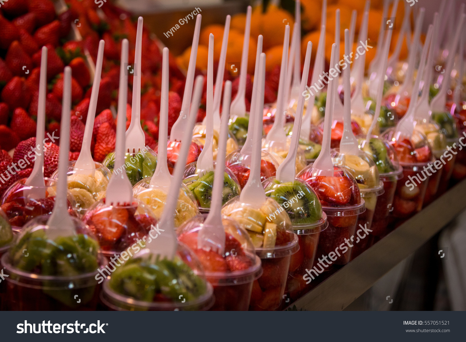 fruit salad arranged in plastic cups with forks at the market