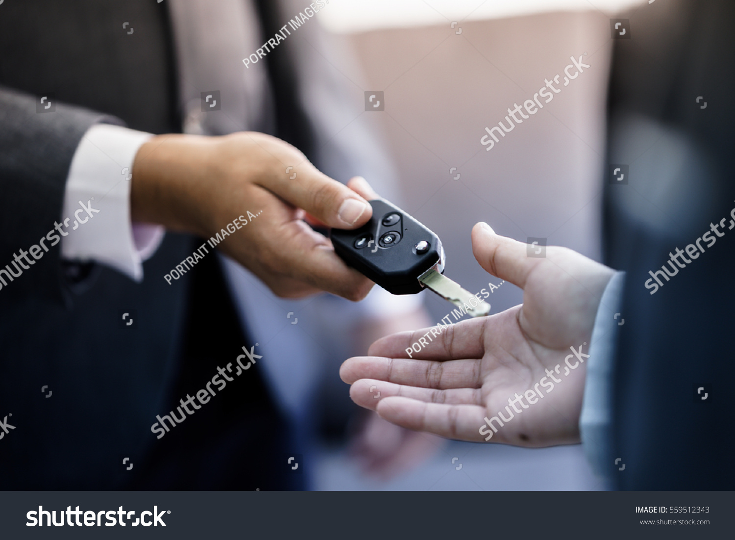 Car salesman handing over the keys for a new car to a young businessman