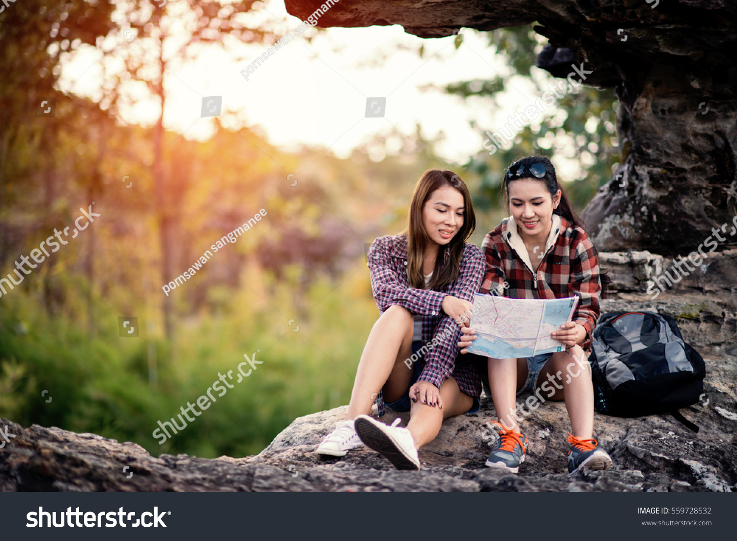 two woman with trendy look searching direction on location map while traveling abroad in summer