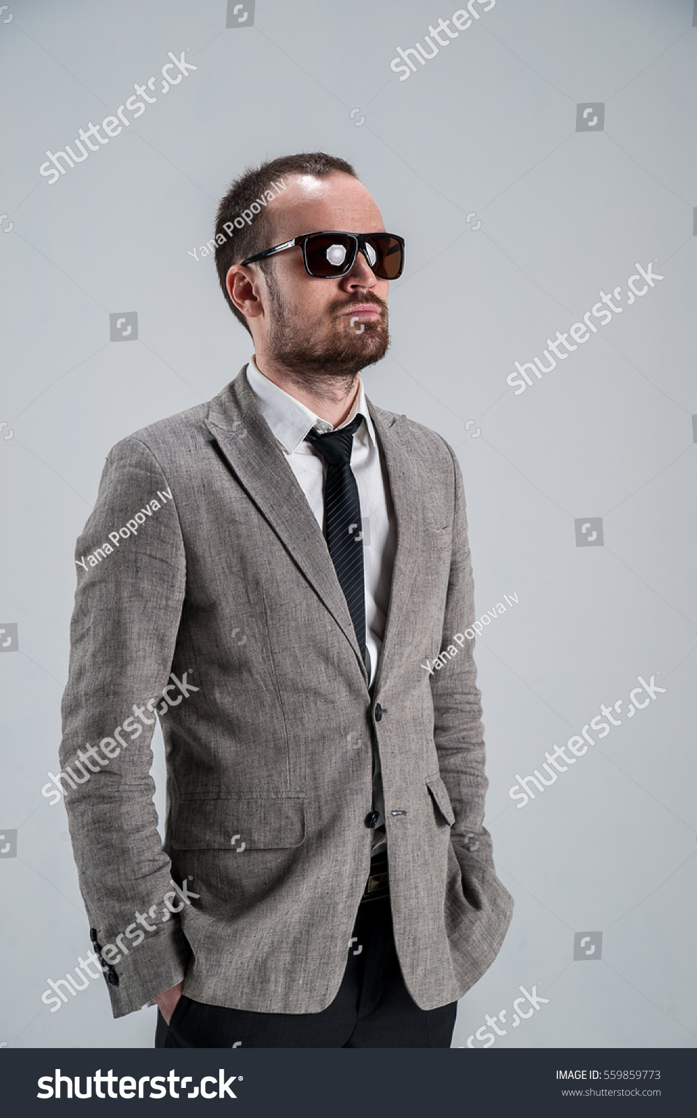 seriousbusinessmaninglassesholdinghandsinthepocketsofhispantsin