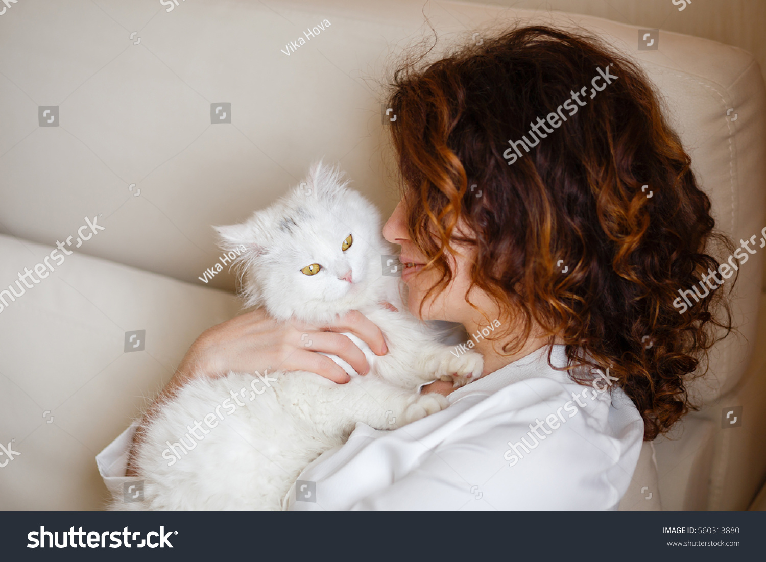 Cute girl with curly hair hugging white fluffy cat