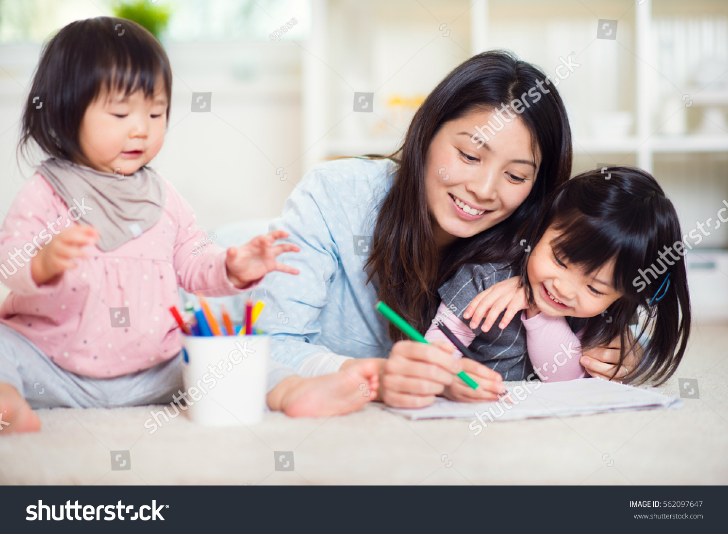 Pretty happy japanese mother play with her two cute little daughters at home