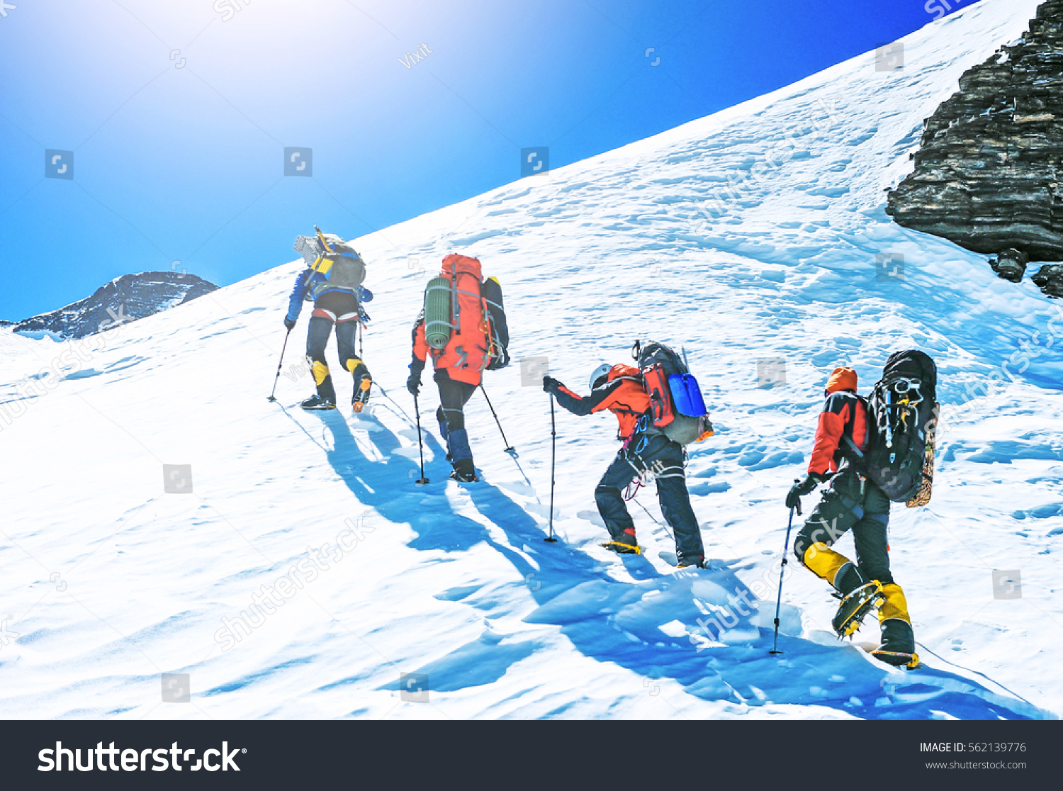 Group of climbers reaches the top of mountain peak. Climbing and mountaineering sport. Teamwork concept.
