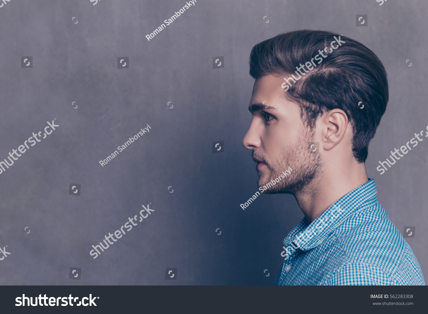 Profile of handsome smiling young man on gray background