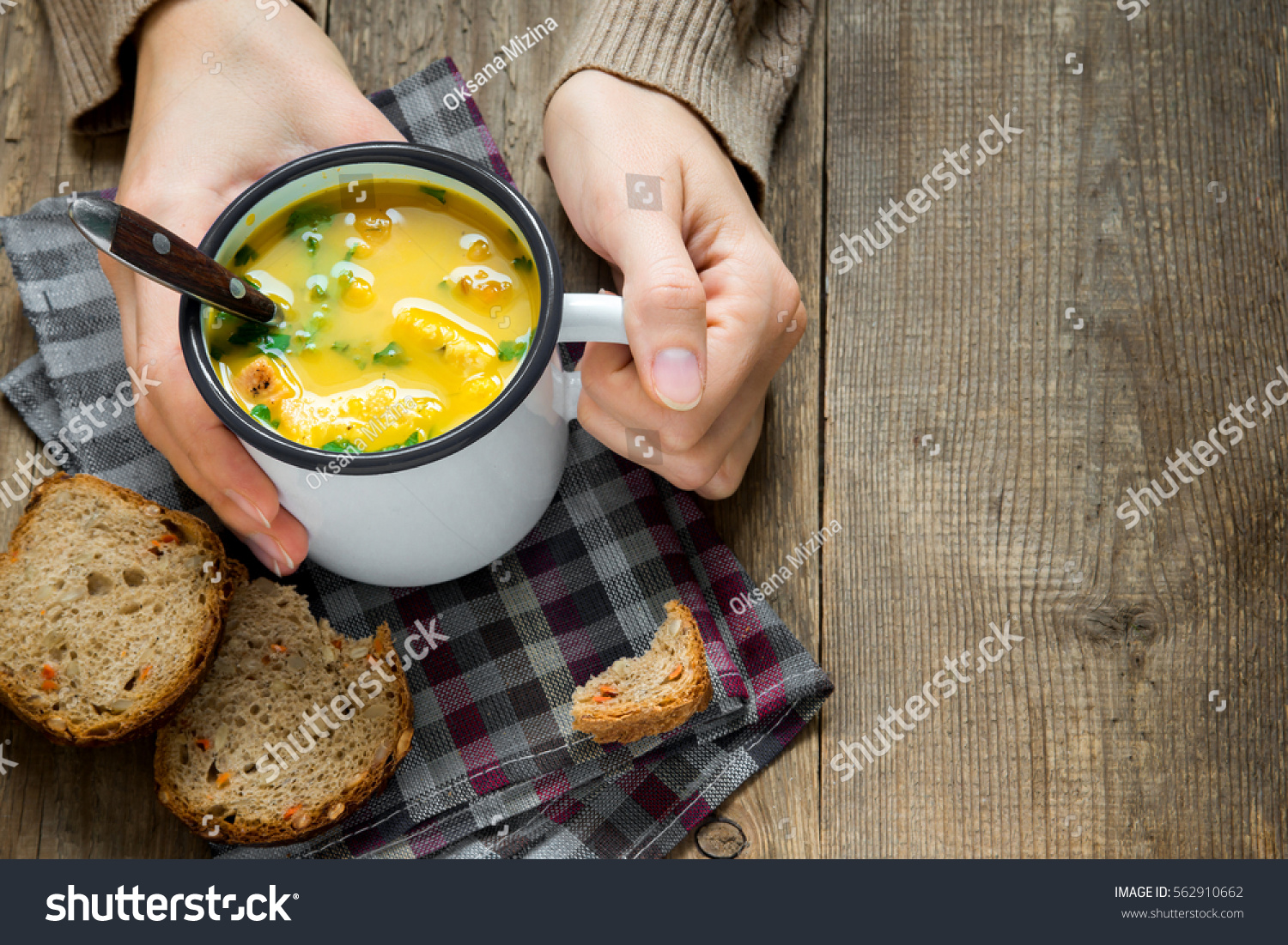 Woman hands holding mug of vegetable soup with parsley and croutons over wooden background - healthy winter vegetarian food