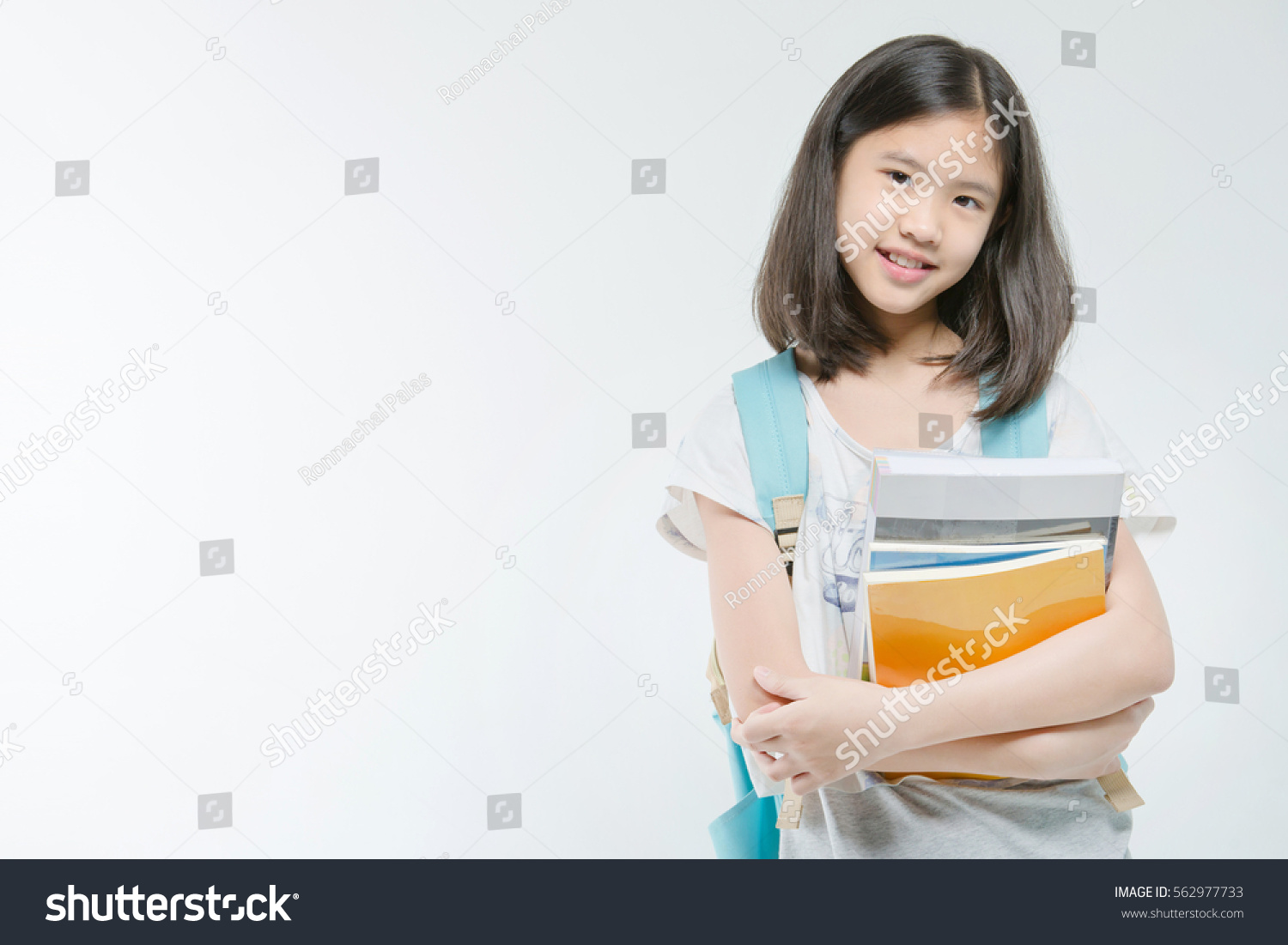 Young Asian student girl holding books on isolated background