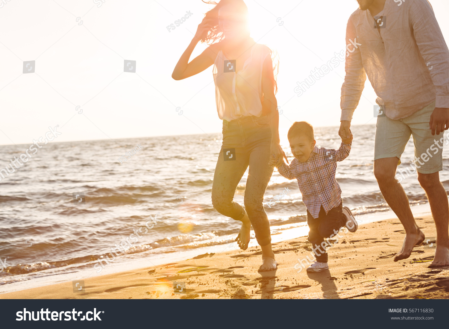 happy young family have fun on beach run and jump at sunset