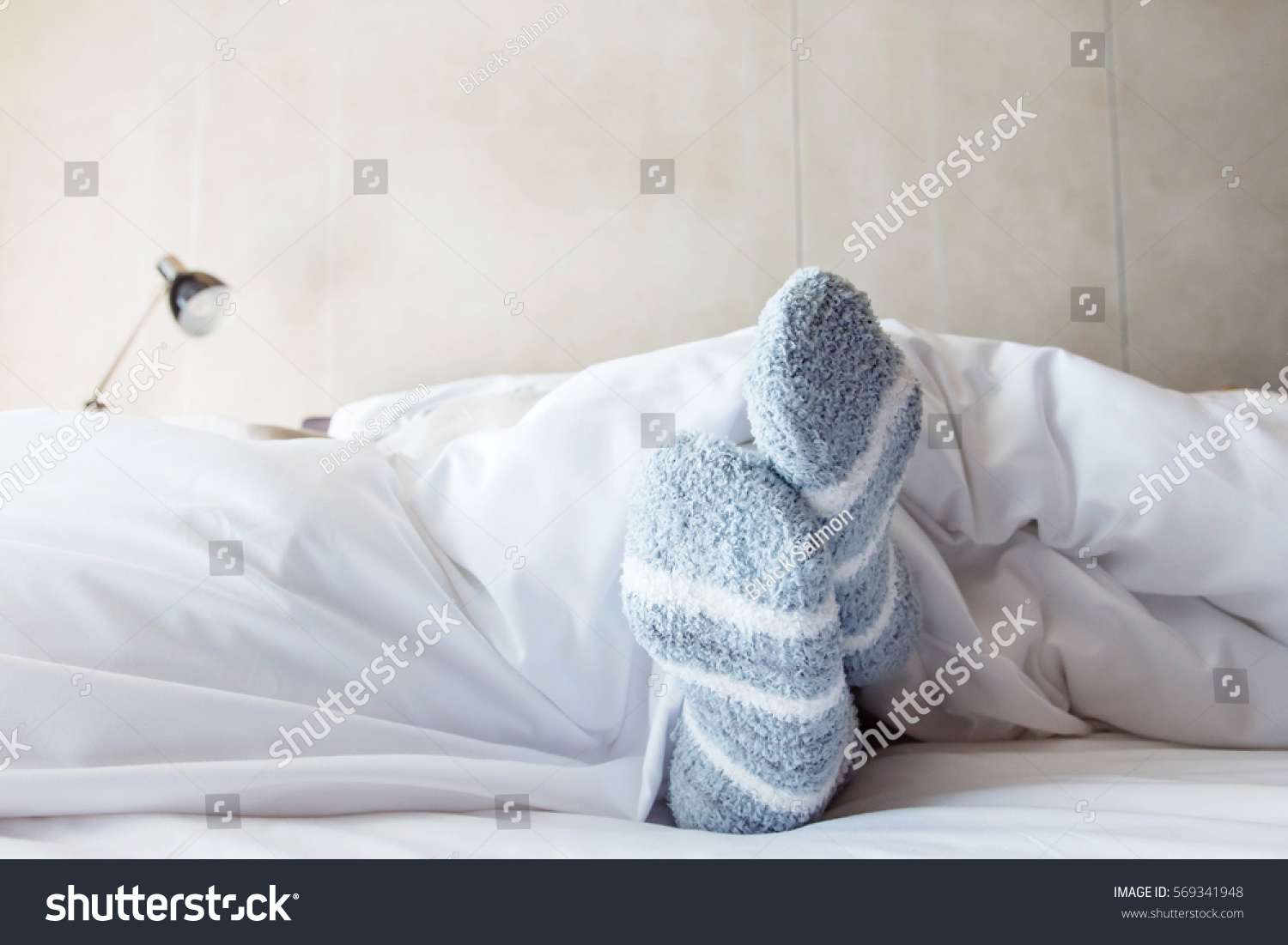 Female foot in warm Stripe wool sock Woman Sleeping and Relaxing in bed concept Rare View