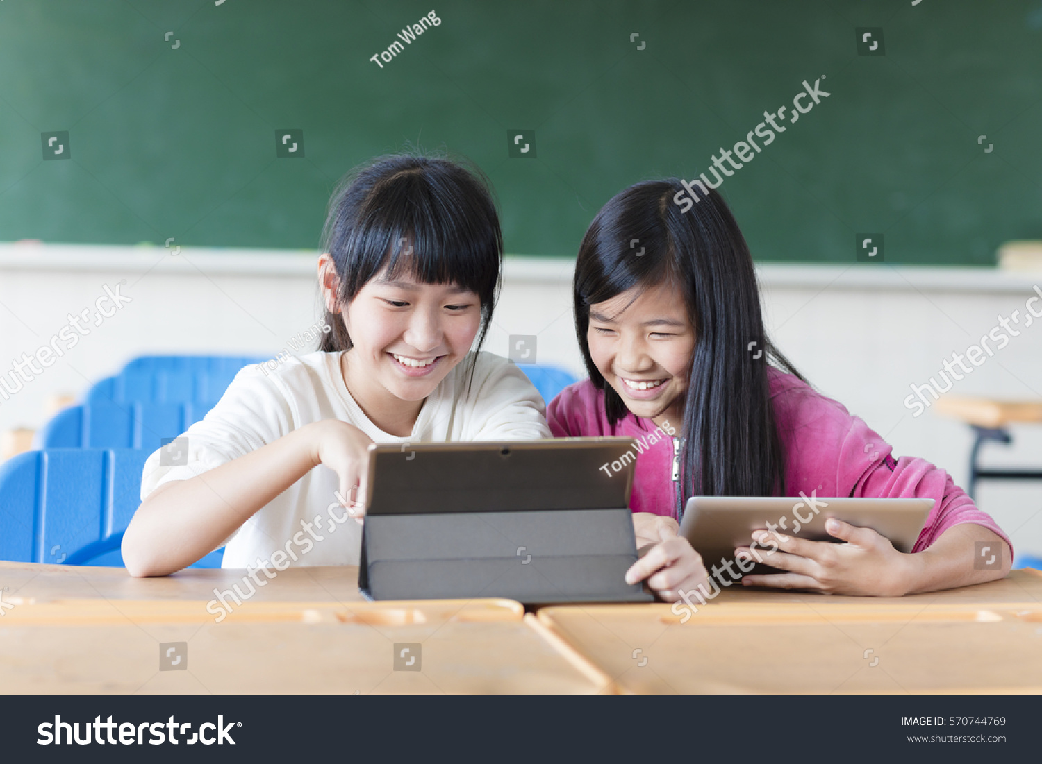 Two teenage girls student watching the tablet in classroom
