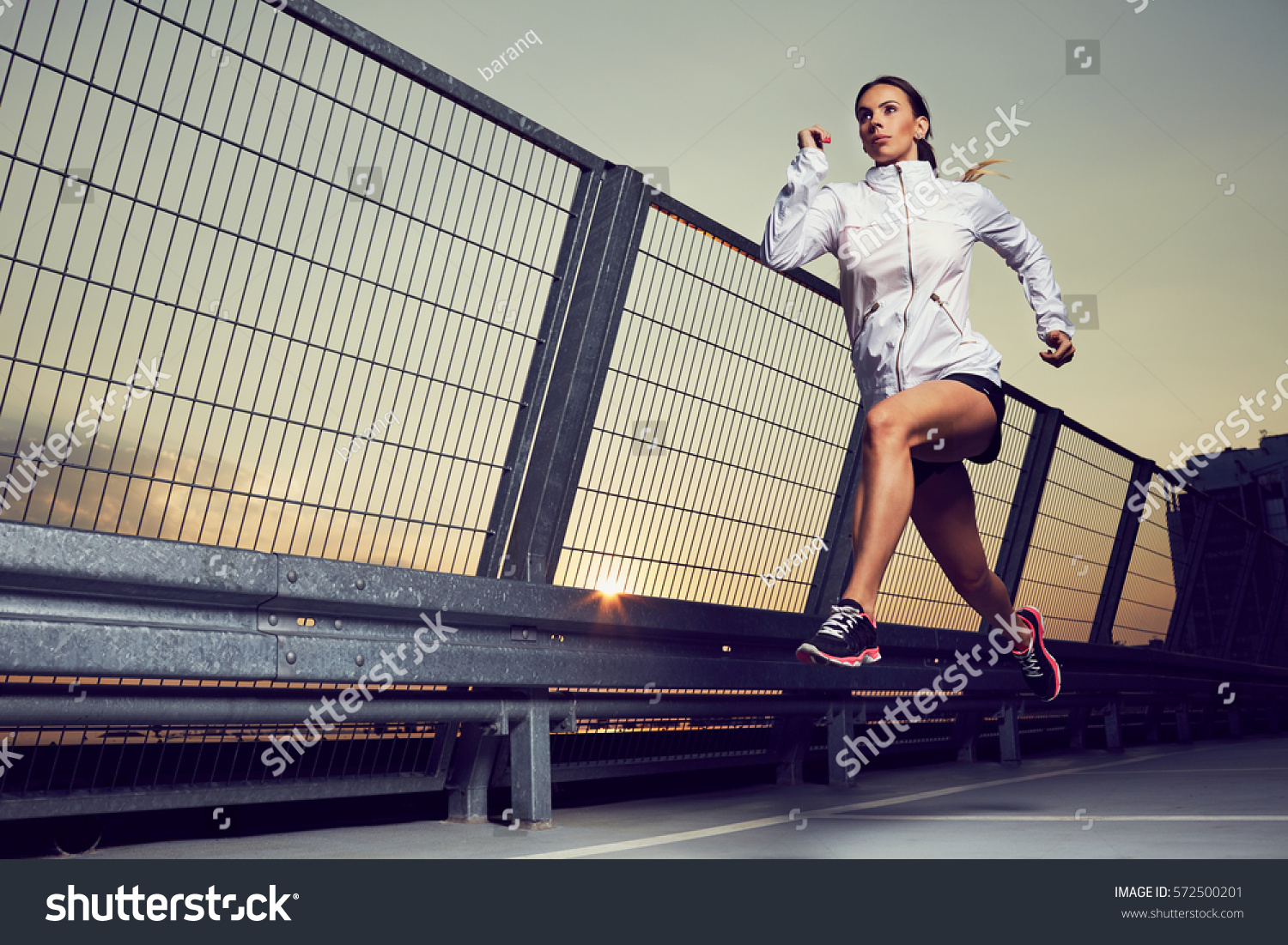 Athletic woman running during sunset on rooftop of parking  garage